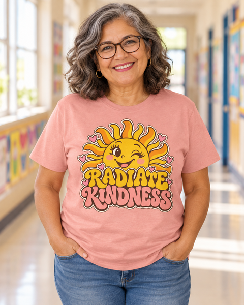 Teacher wearing peach RADIATE KINDNESS tee with its original smiling sun